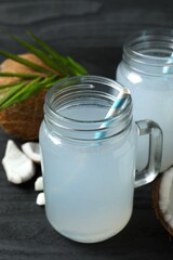 Mason jars with coconut water with nuts on wooden table