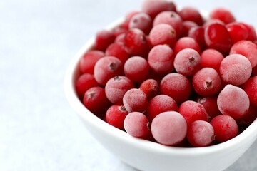 Frozen cranberries in a bowl on a gray background