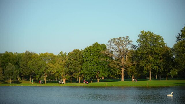 Golf course amidst water, natural landscape. The background with a lush green landscape with trees and people walking or relaxing Wide footage