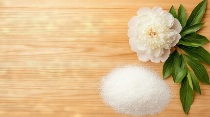 Naklejka premium A white blossom rests atop a wooden surface near a heap of salt and a sprig of emerald foliage