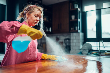 Woman cleaning kitchen counter with spray bottle
