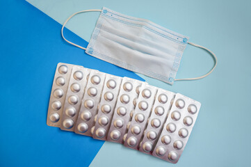 tablets in silver blisters and a medical mask on a blue background