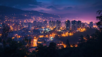 Fototapeta premium Cityscape at twilight, illuminated buildings, mountain backdrop, aerial view
