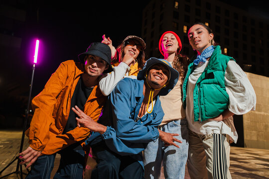 Group of Young Adult Friends Posing Cheerfully in Urban Street wear Fashion with Energetic Expressions. HipHop Dancers Posing for a Fun and Vibrant Social Media Photo Shoot at Night Lifestyle