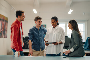 Young professionals collaborating on project using digital tablet in modern office
