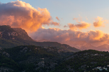 Breathtaking sunset over picturesque harbor of Port de Soller, Mallorca, with sky painted in warm hues reflecting on calm Mediterranean waters. Serene coastal scene capturing beauty dusk.