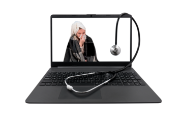 Laptop and medical stethoscope on a transparent background. On the laptop screen - a girl with cold symptoms blows her nose into a paper handkerchief