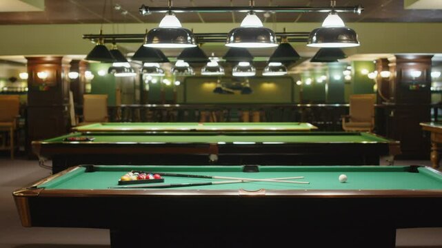 No people panning shot of interior of modern night club with multiple baize billiard tables prepared for playing