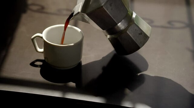 Close up at the hands of a male barista placing coffee in a white cup, using an Italian mocha.