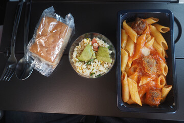 Lunch served during a flight with pasta and salad on a tray