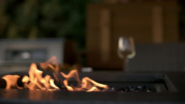 Cozy Outdoor Firepit with Glass of Wine Warm flames from outdoor firepit create cozy atmosphere, with glass of wine in background, perfect for relaxing evening outdoor firepit