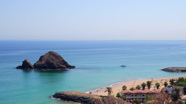 Snoopy Island in Fujairah, UAE. Aerial view of the beach with turquoise waters, a rocky island and a resort nearby