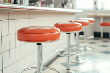 Close-up of vibrant orange retro-style bar stools lined up at a counter, showcasing a nostalgic and...