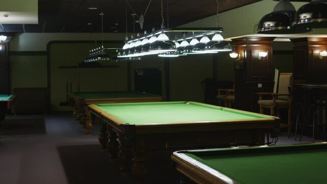 No people full shot of baize billiard table illuminated by lamps from above in public club in evening