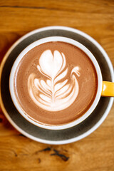 Cup of cocoa with milk art on wooden table in the morning at breakfast