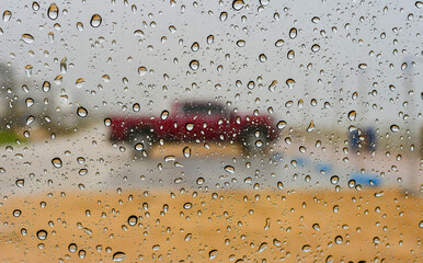 Raindrops on the glass, car in the center of the frame.