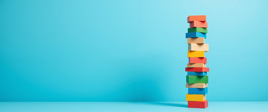 Colorful building blocks stacked high against a bright blue background, conveying a sense of stability and teamwork, representing the foundation of Effective Leadership