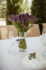 A glass of wine and a vase of flowers on a table