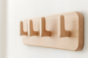 Wooden coat rack with multiple hooks on a white wall. Minimalist design with light wood. Stylish and functional home decor element.