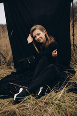 Obraz premium beautiful woman dressed in black pants and sweater sits on a black background with a beautiful black Labrador dog. Labrador Retriever dog