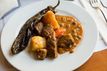 Juicy beef stew in gravy served with with marinated pepper on plate