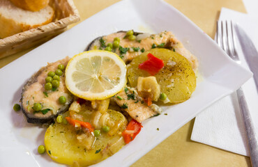 Delicious fried salmon fillets served with lemon, potato, bell peppers and greens peas. High quality photo