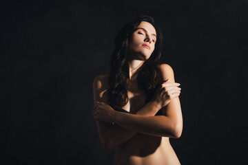 Photo of chic girl touch hug herself feeling tempting comfy with eye closed on dark color background