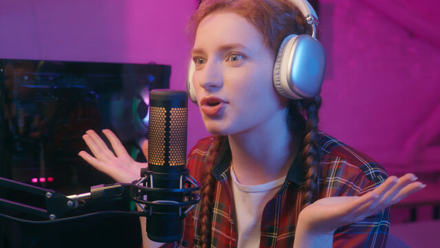 Woman teen girl smile female gamer streamer influencer blogger wear headphones radio host gaming podcast online stream cyber sport championship comment play video game talk record mic in neon studio