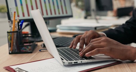 Close-up of silver latop standing on wooden desk, dark-skinned man working on it, young hands, typing text into keyboard, tapping fingers on computer