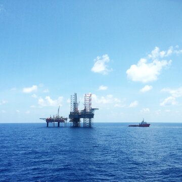 Oil and gas platform in sea with an offshore vessel transporting cargo