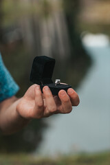 Close up of man hands holding engagement ring box on the beach