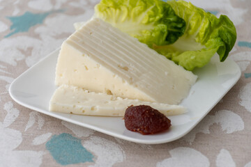 Spanish hard manchego, cow, sheep and goat cheese served for breakfast with green salad leaves and Membrillo quince cheese close up