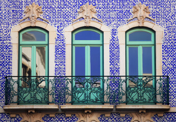 Traditional Portuguese building facade with azulejo tiles, balcony, and vibrant colors.