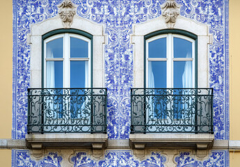 Traditional Portuguese building facade with azulejo tiles, balcony, and vibrant colors.