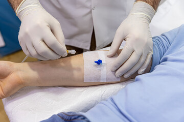 The doctor inserts a needle into the vein of the patient. Nurse connecting an IV drip. Nurse...
