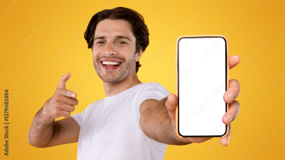Poster Check This Website. Portrait of smiling male holding smart phone with white blank screen in hand, showing device close up to camera and pointing finger at gadget with empty free space for mock up