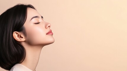 Naklejka premium Profile of beautiful young asian woman with closed eyes, perfect skin and light pink lipstick is posing on beige background with copy space
