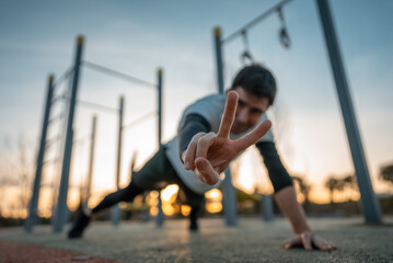 young athletic man exercising at fitness calisthenics workout and standing plank at street gym...
