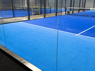  blue court for padel with construction created by mesh and the glass back walls.