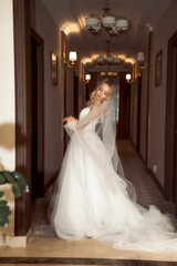 Fototapeta premium beautiful blonde bride with veil posing in hotel lobby in fashionable dress