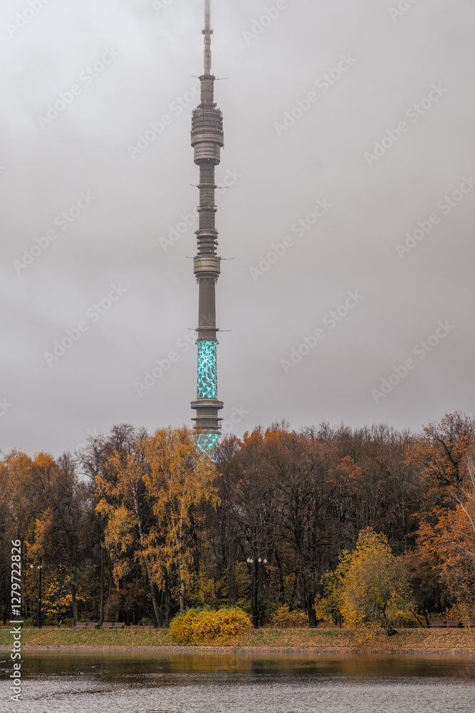 Poster tower surrounded by autumn trees near the water in a cloudy setting showcasing illumination in the e