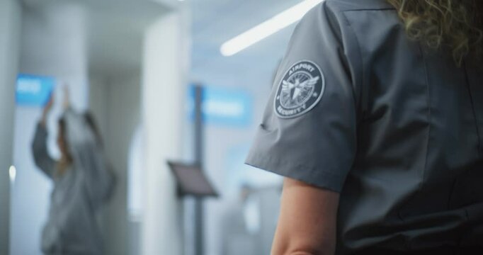 Airport Security Checkpoint: Female Security Officer Inspects Young Woman Body for Suspicious Items After X-ray Metal Detector Scanning Gates. TSA Screening Procedures. Tourist Going on Holiday Trip.