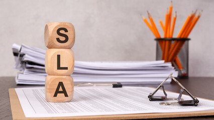 SLA concept with wooden cubes and office supplies on a desk, symbolizing service level agreement