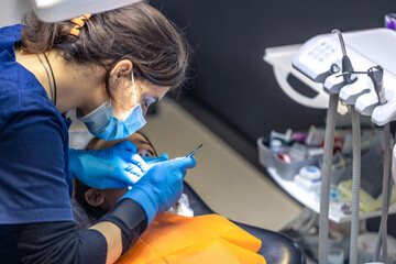 The dentist treats the child's tooth using a rubber dam. Close-up of tooth treatment.