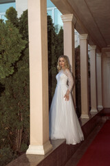 Obraz premium beautiful blonde bride posing in open gallery of hotel. in long wedding dress