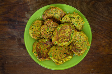 Gratin zucchini with cheese and greens on a wooden background. Delicious homemade food.