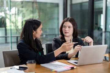 Engaged female colleagues reviewing project plans and collaborating on analysis in a contemporary office.