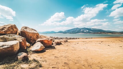 A wide shot of a sandy beach with large rocks framing the view, open space for copy.