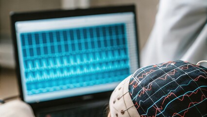 A closeup of a braincomputer interface device p on the temples with neural signals visually represented on a nearby screen illustrating the direct connection between thoughts and