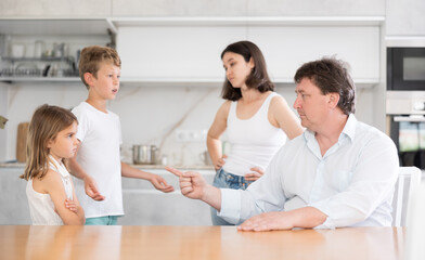 Obraz premium Parents condemn their guilty two children standing in kitchen in apartment..